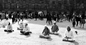 5 ways to transform agitation into calm with mindfulness: Group meditation in busy public square.