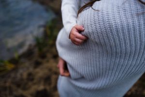4 ways to practice mindfulness in motherhood: A woman in a white jumper holds her baby.