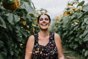 4 ways mindfulness enhances happiness: A laughing woman stands between two hedges as confetti is thrown at her.